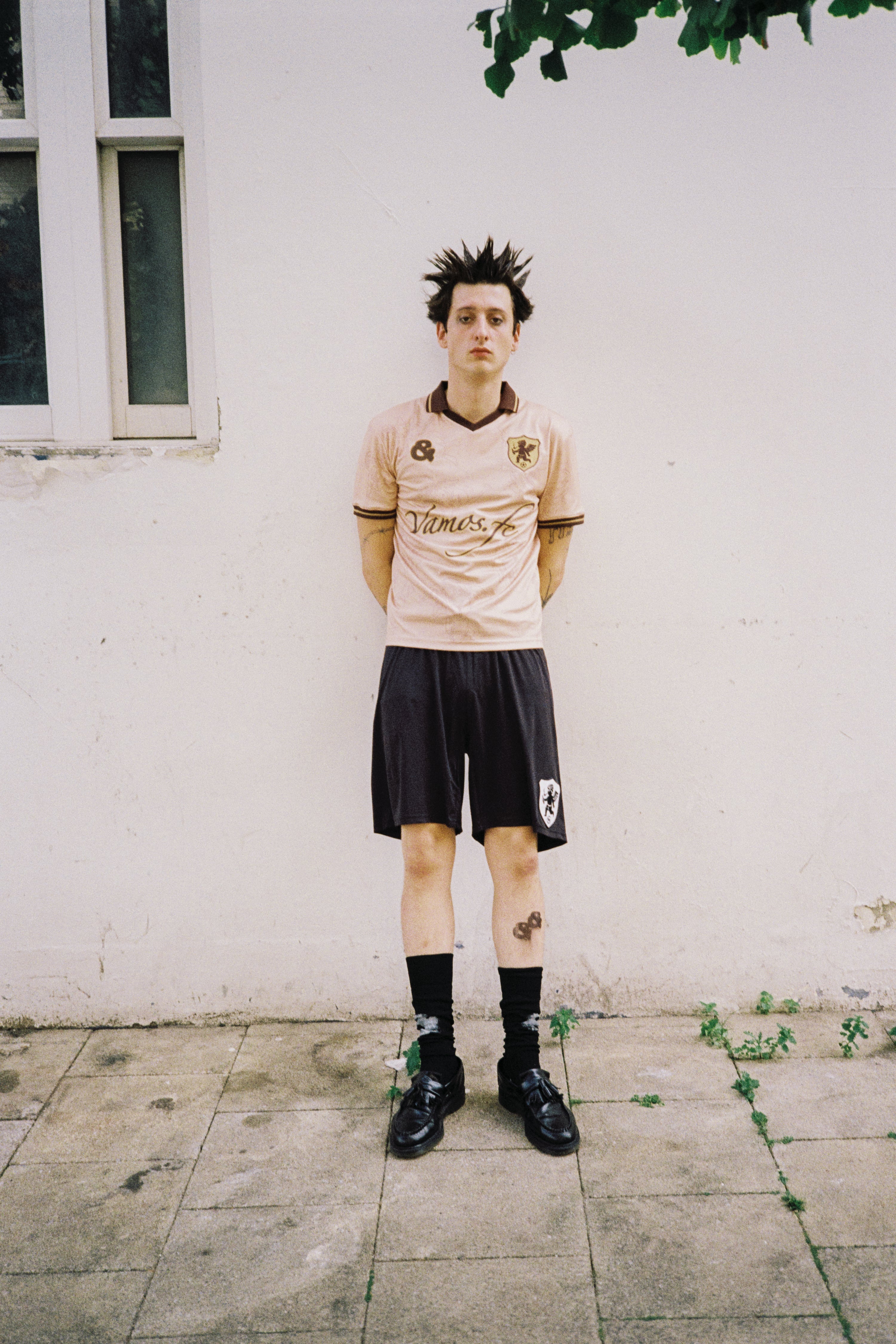 Model wearing the andvamos Footy Shirt — cream limited-edition football shirt styled as streetwear, full look
